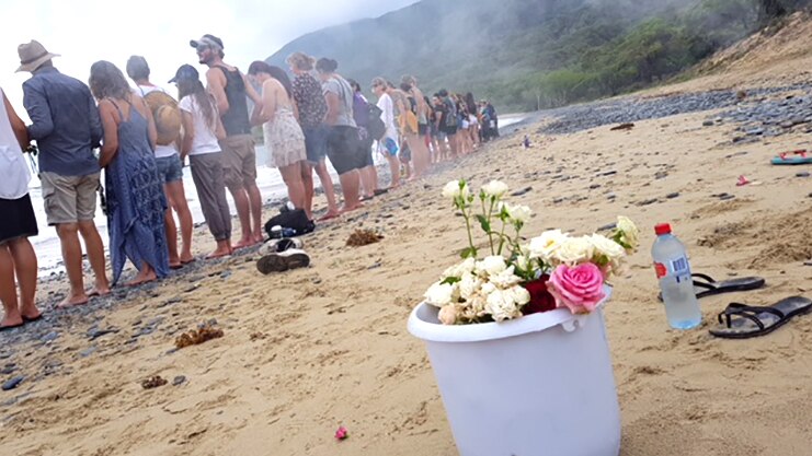 Residents with flowers form a human chain across Wangetti Beach to remember Toyah Cordingley, who was found dead there.