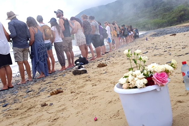 Residents with flowers form a human chain across Wangetti Beach to remember Toyah Cordingley, who was found dead there.