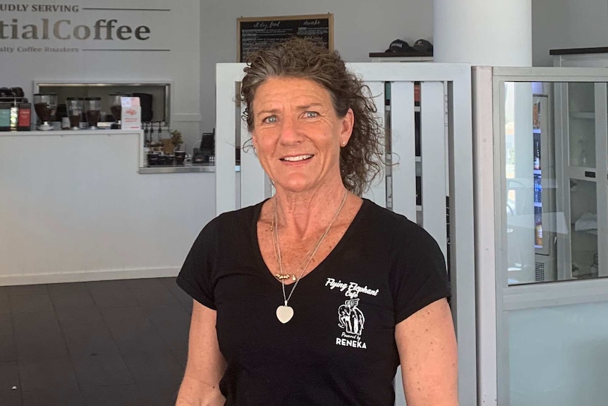 A woman standing outside her street cafe