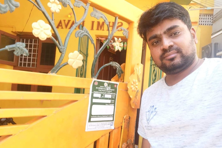 Navin Chandhar Chittatoor standing next to a notice in Hindi on his family's compound