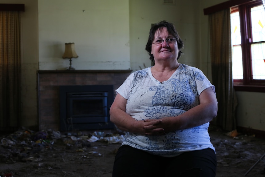 A woman sits in a flooded home