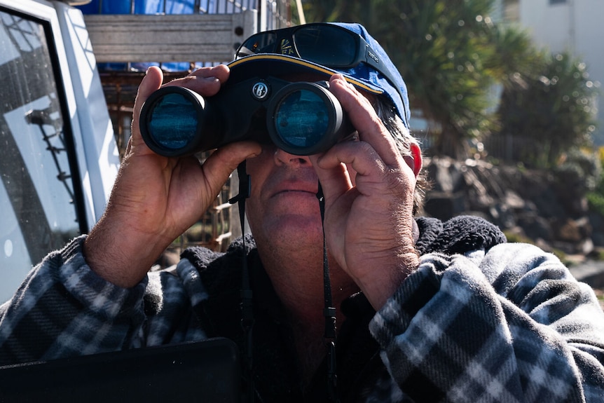 man using binoculars on beach
