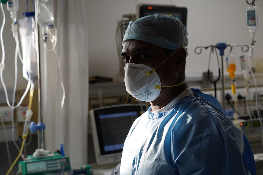 A man in a face mask and hospital scrubs