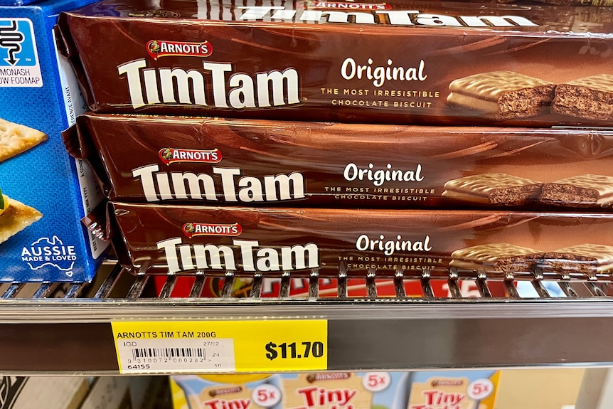 Packets of Tim Tam biscuits on a shelf, with a price tag saying $11.70