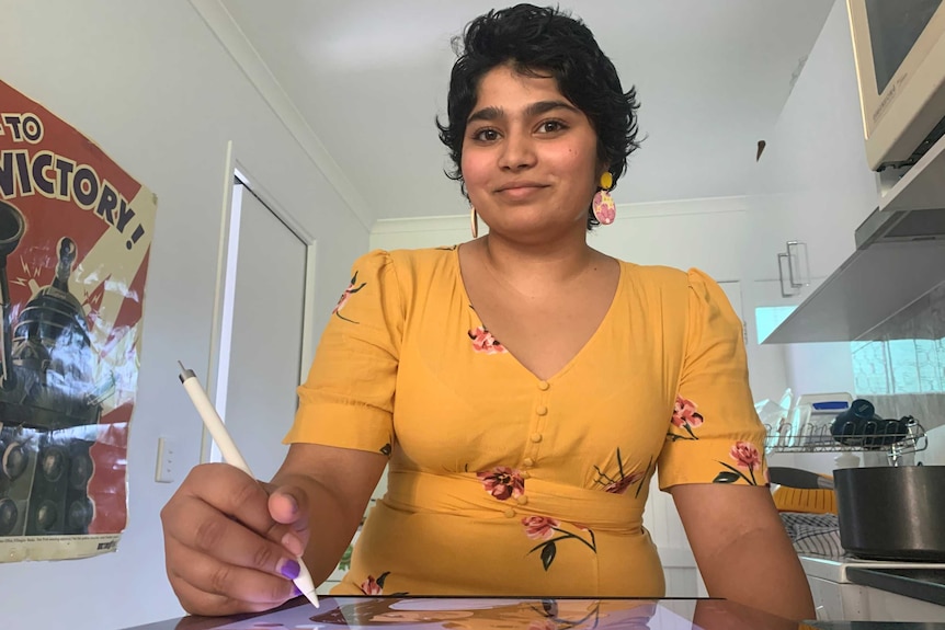 Amber Pereira sits at home holding a pen on her tablet.