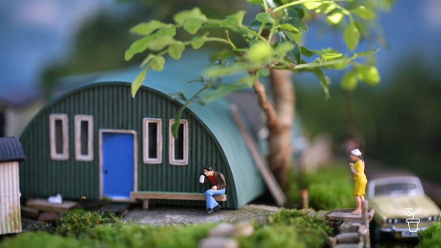 Diorama with garden scene and model of nissen hut and model people and car