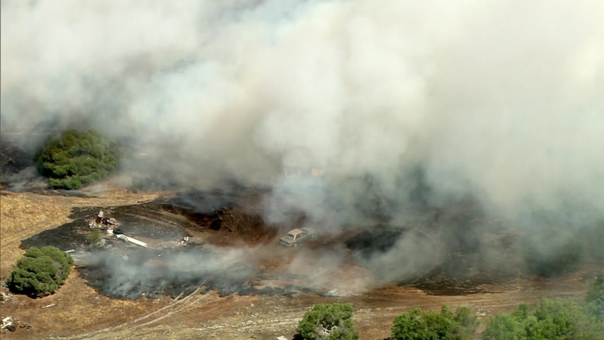 Smoke from a fire with a car pictured in the middle of the shot