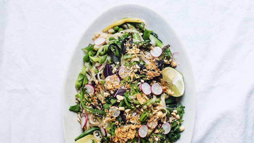 Spring pad thai salad with purple basil, shallots, peas and beans on a serving platter.
