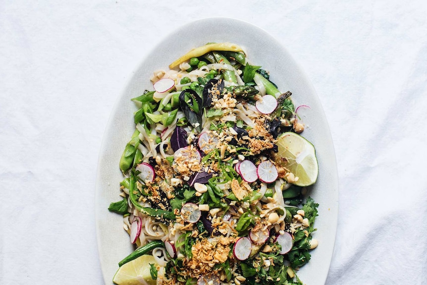Spring pad thai salad with purple basil, shallots, peas and beans on a serving platter.