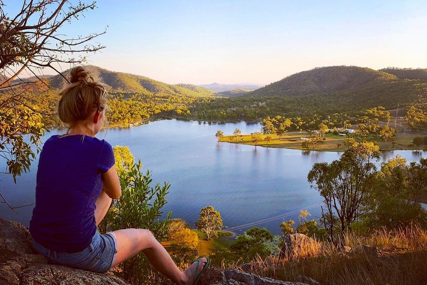 A woman overlooking a dam just after dawn