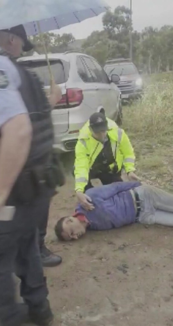 A man on the ground with a police officer assisting him.