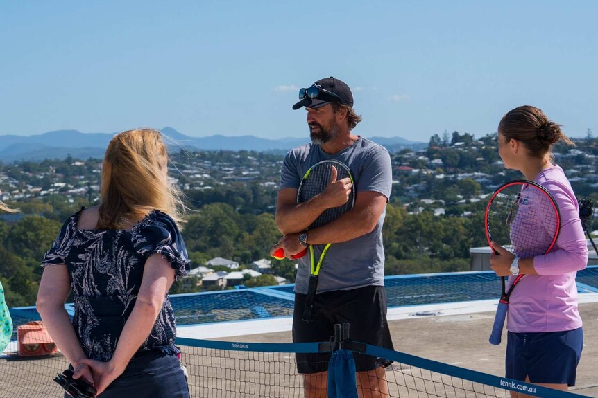 Two ladies speaking to Patrick Rafter and Ash Barty holding tennis racquets.