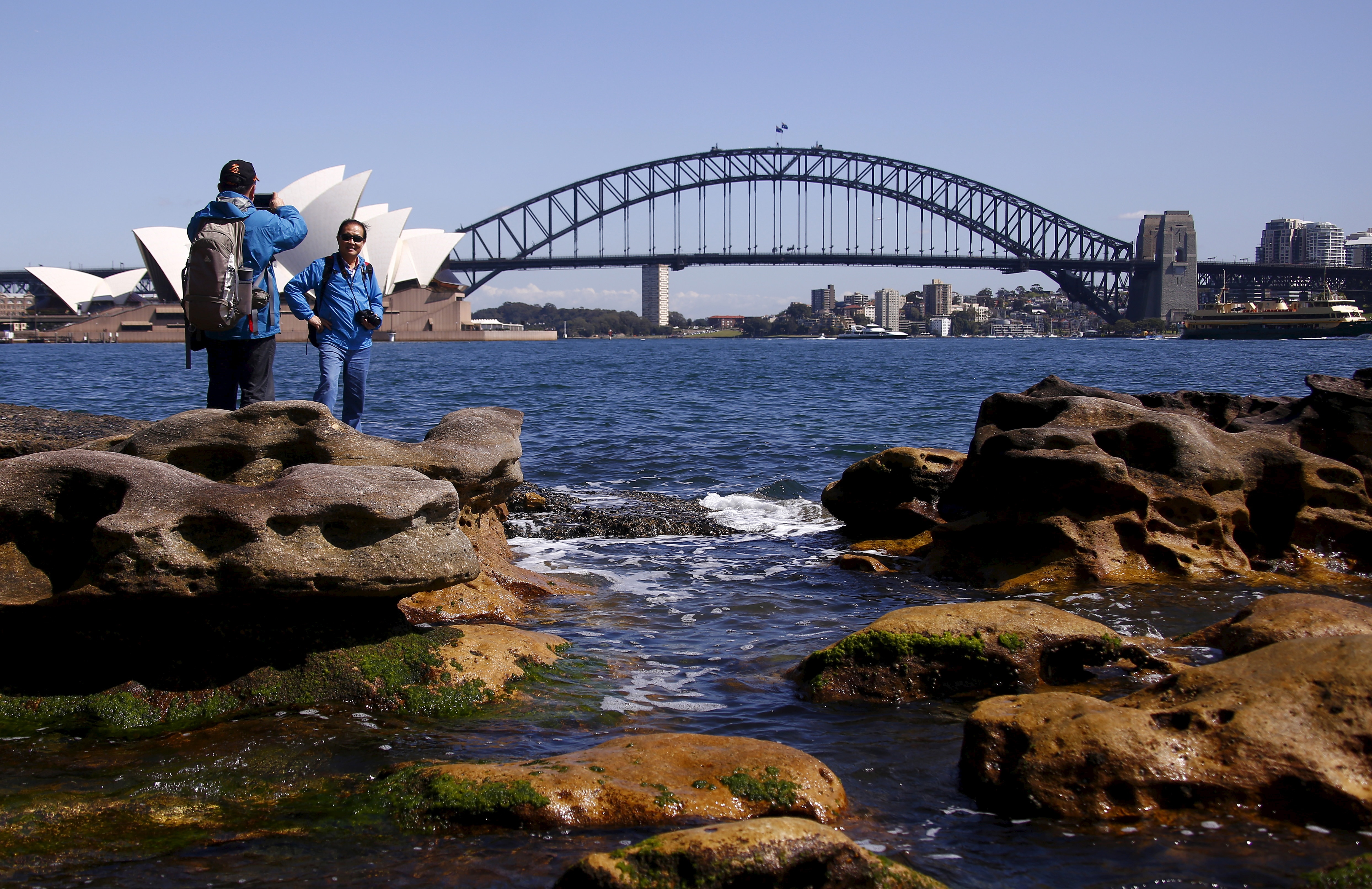 Dos hombres se toman fotos frente a la Ópera y el Puente del Puerto de Sydney 