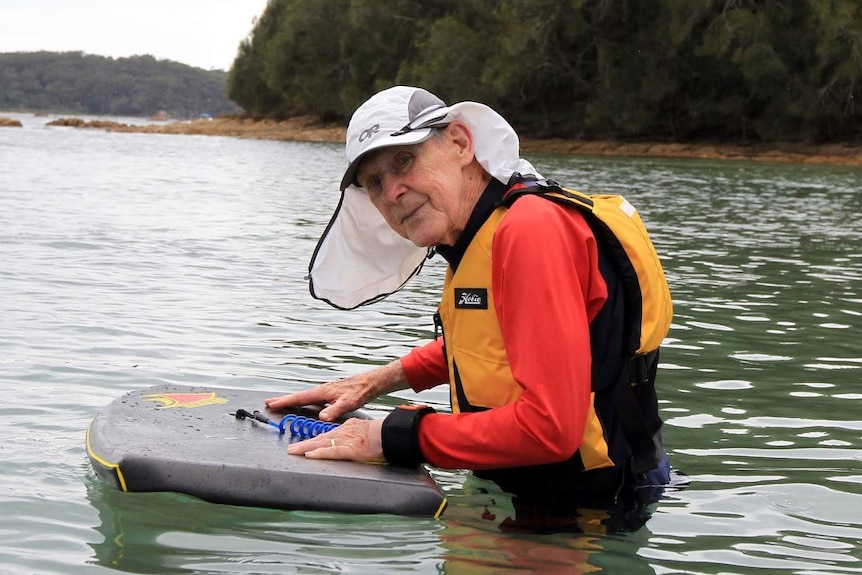 Elderly man in water with boogie board