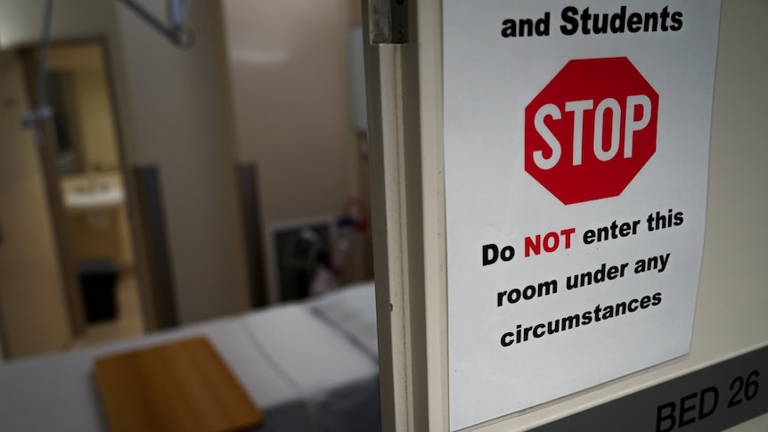 A sign which says 'Do NOT enter this room under any circumstances' with a hospital room.