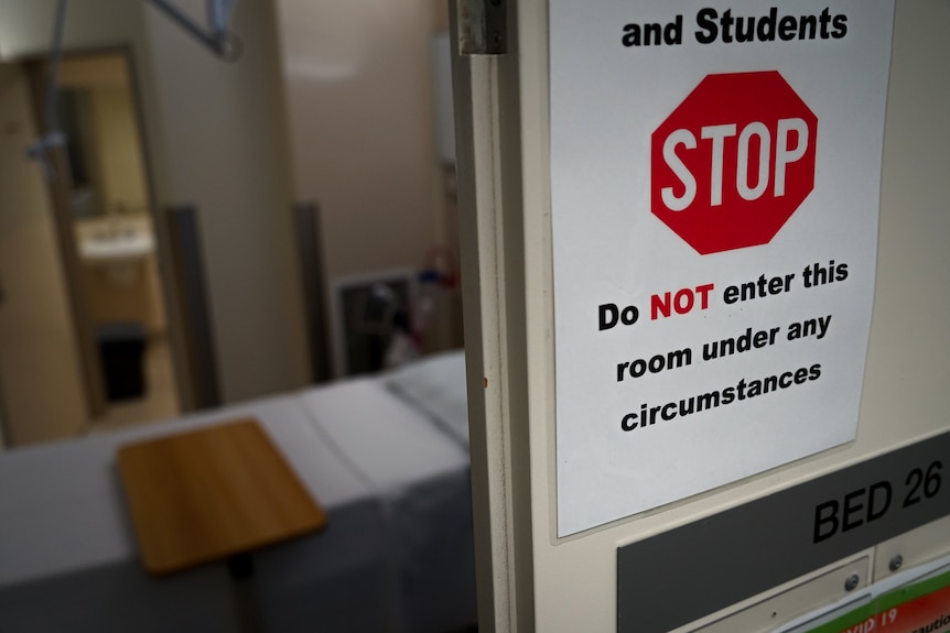 A sign which says 'Do NOT enter this room under any circumstances' with a hospital room.