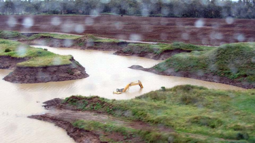 Excavating equipment is partially submerged in a flooded quarry in Moree