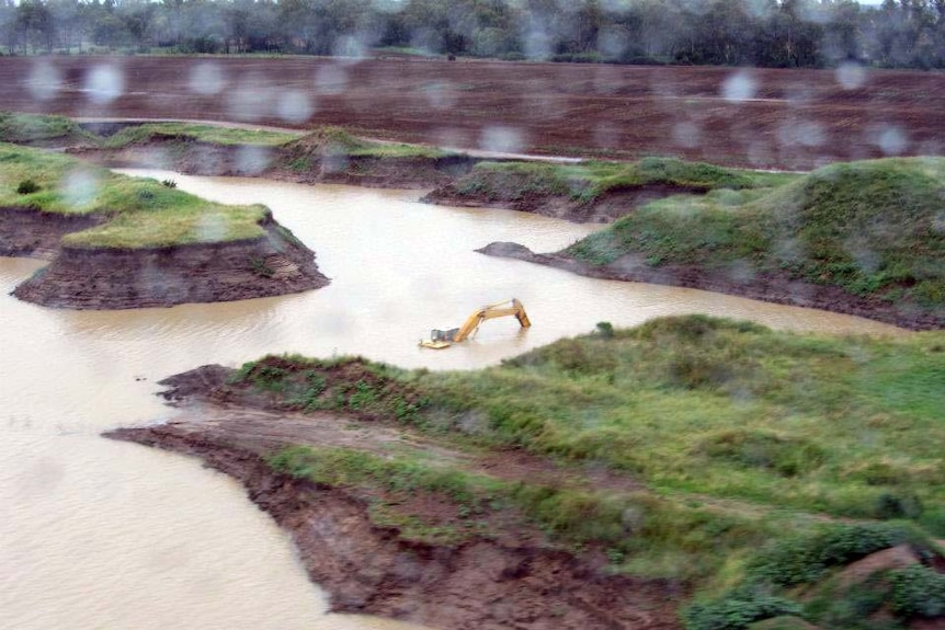 Excavating equipment is partially submerged in a flooded quarry in Moree