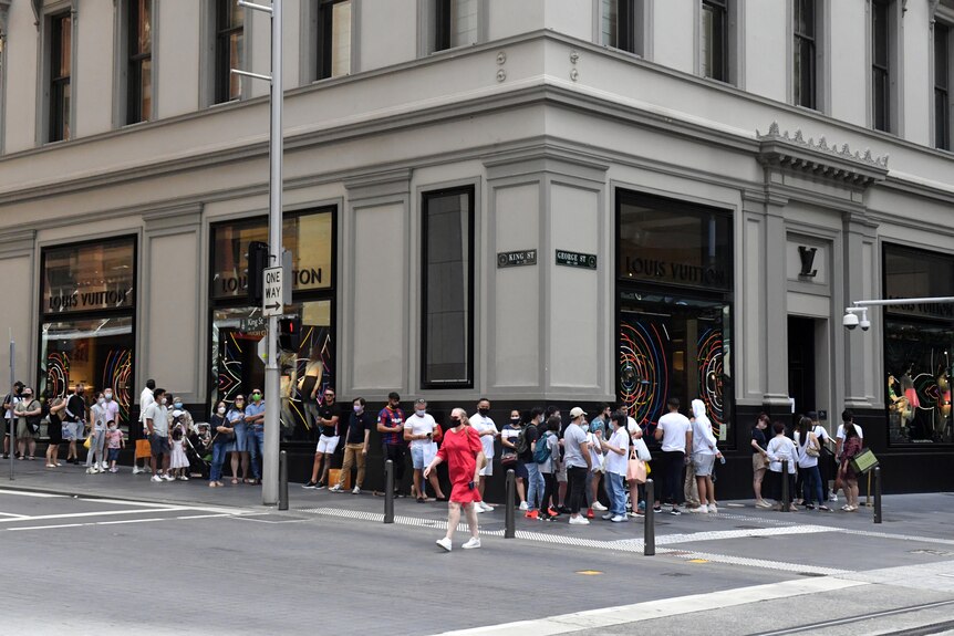 Shoppers queue around a building