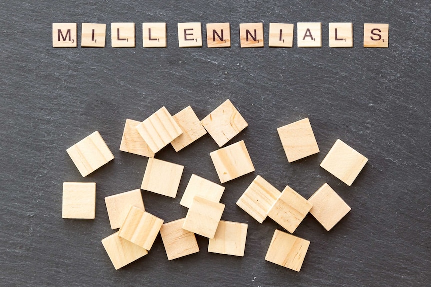 Scrabble pieces on slate block spelling 'millennials'.