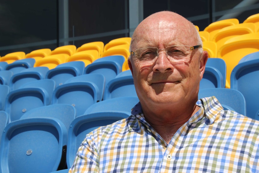 John sits on the football grounds seats.