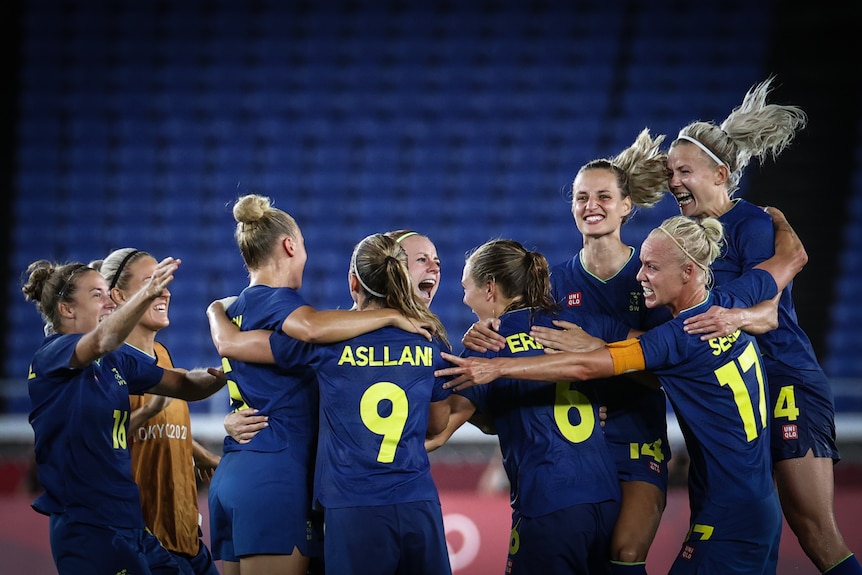 A group of women wearing blue hug each other