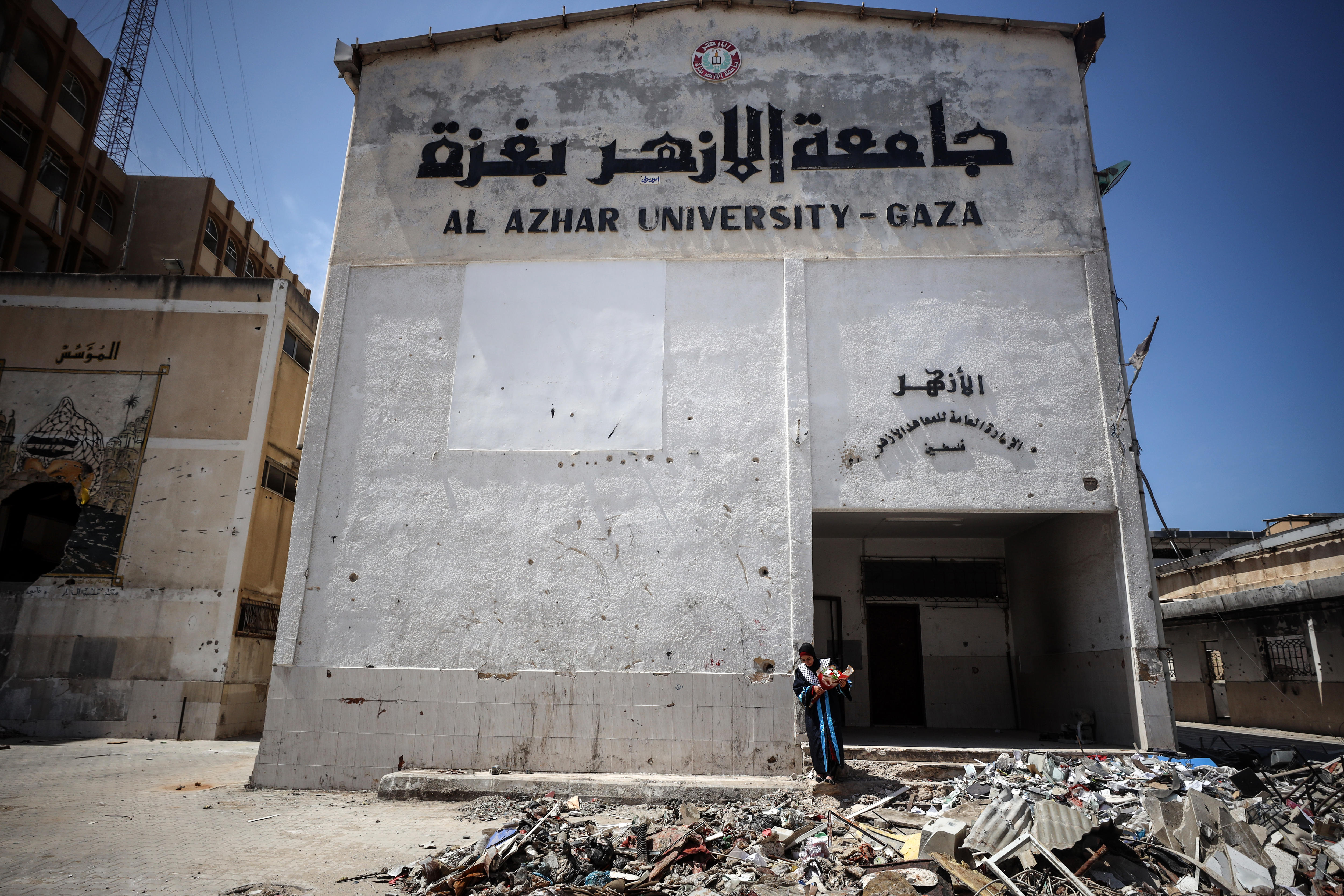 A cream coloured building with a sign reading ‘Al Azhar University Gaza’ surrounded by rubble.