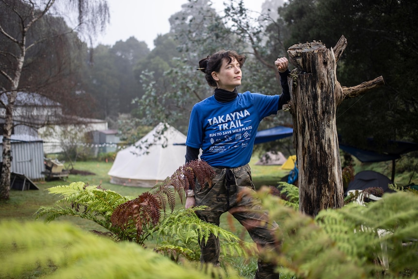 A woman holding on to a tree stump.