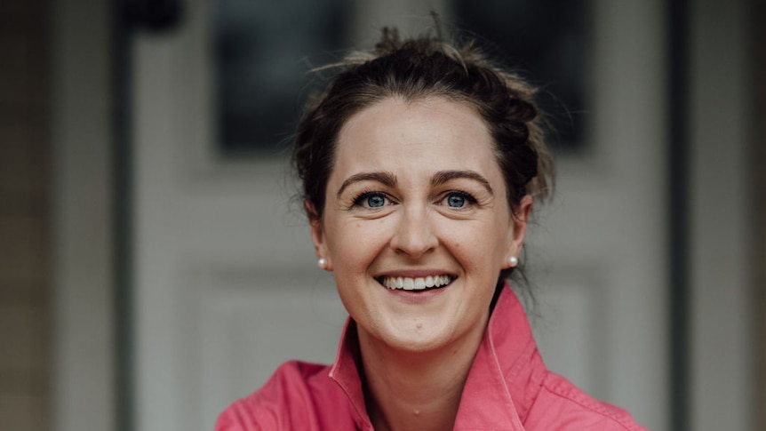 A woman in a salmon-pink shirt poses.