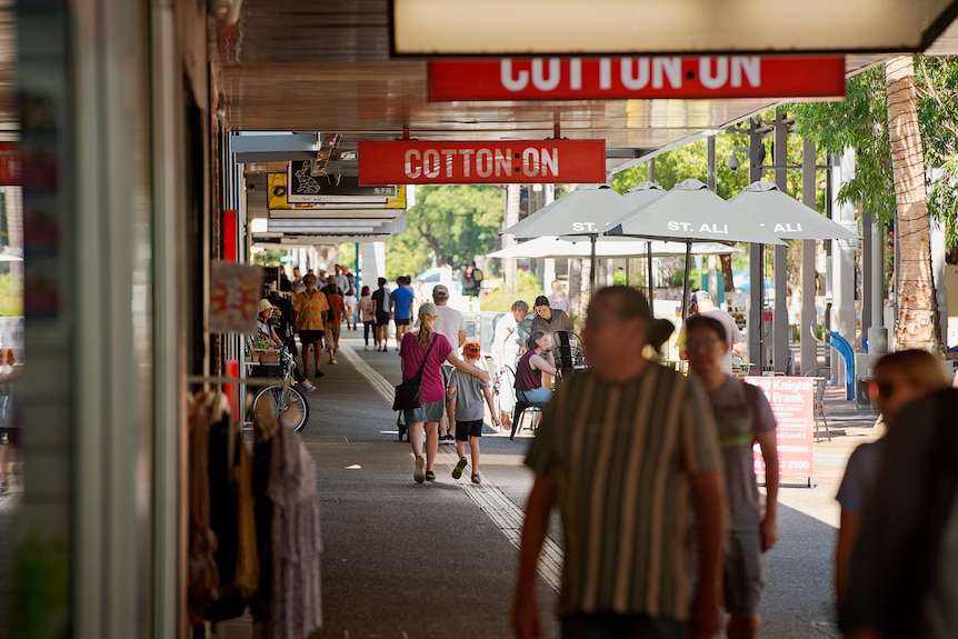 Wide shot of a sunny outdoor mall with people walking up and down the street. 