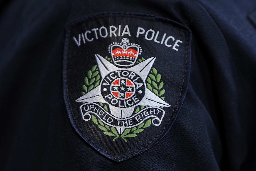 A close-up photograph of a Victoria Police badge on an officer's sleeve.