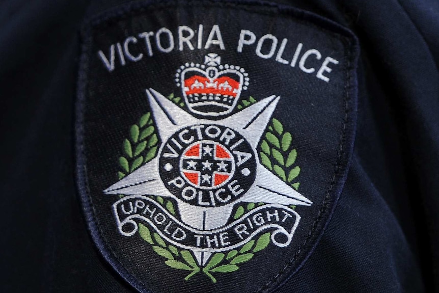 A close-up photograph of a Victoria Police badge on an officer's sleeve.