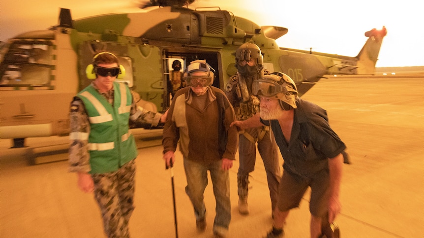 The ADF helping an elderly man out of a helicopter.