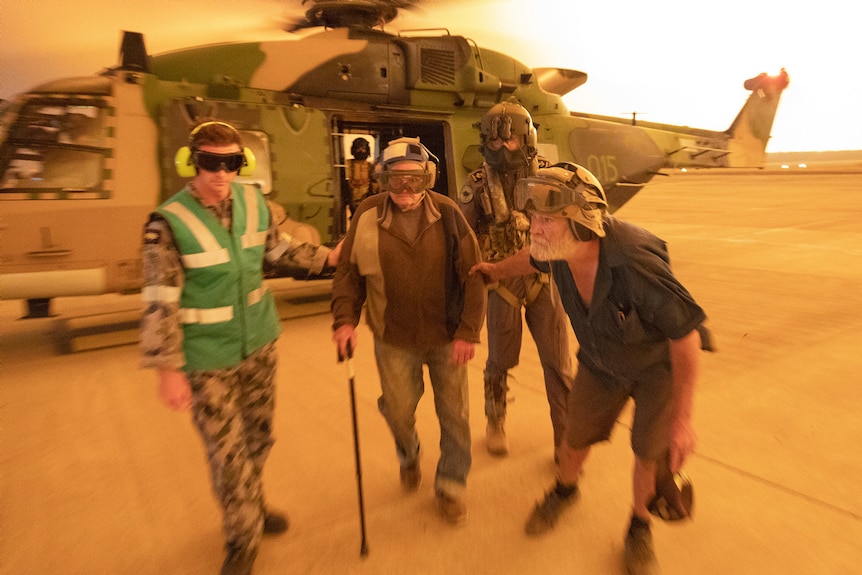 The ADF helping an elderly man out of a helicopter.
