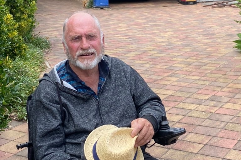 A man in a wheelchair with a bald head. 