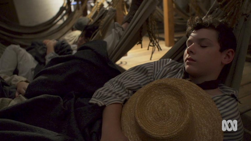 Boy sleeps in hammock in ship hull