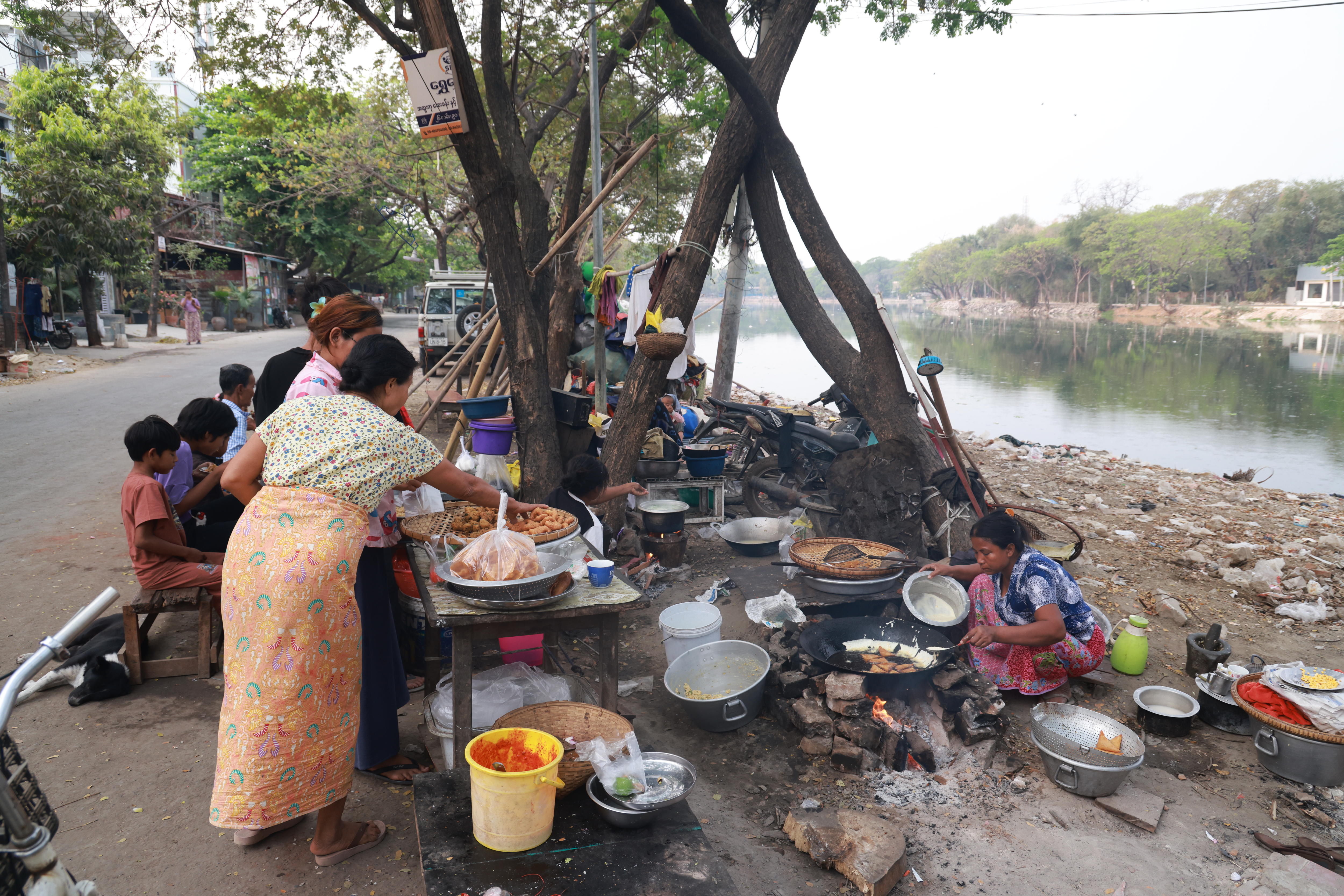 Woman stands near river and silver big dishes nearby.