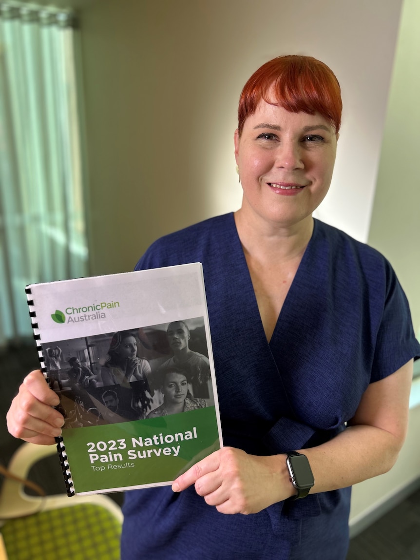 Renee Rankin holds up a bound copy of Chronic Pain Australia's National Pain Survey.