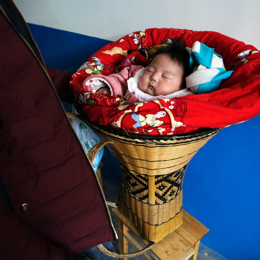 A Chinese baby lies in a cot.