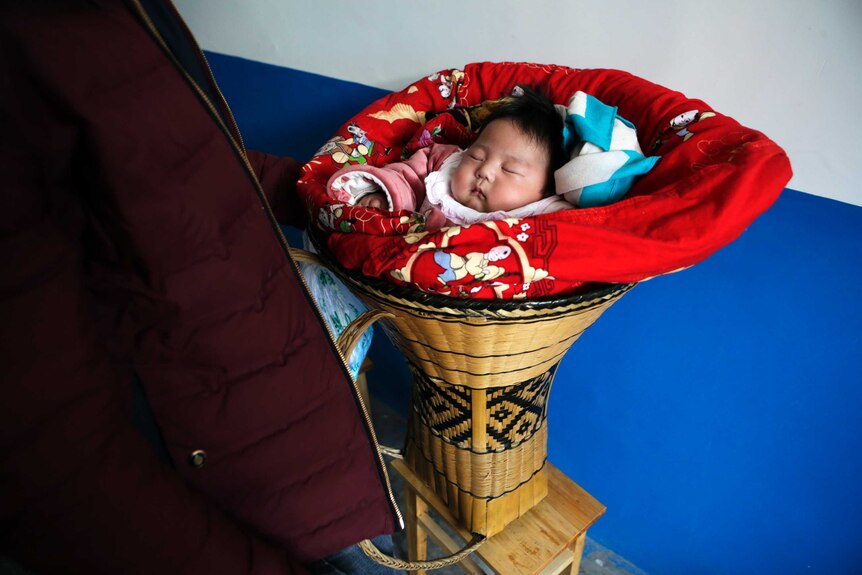 A Chinese baby lies in a cot.