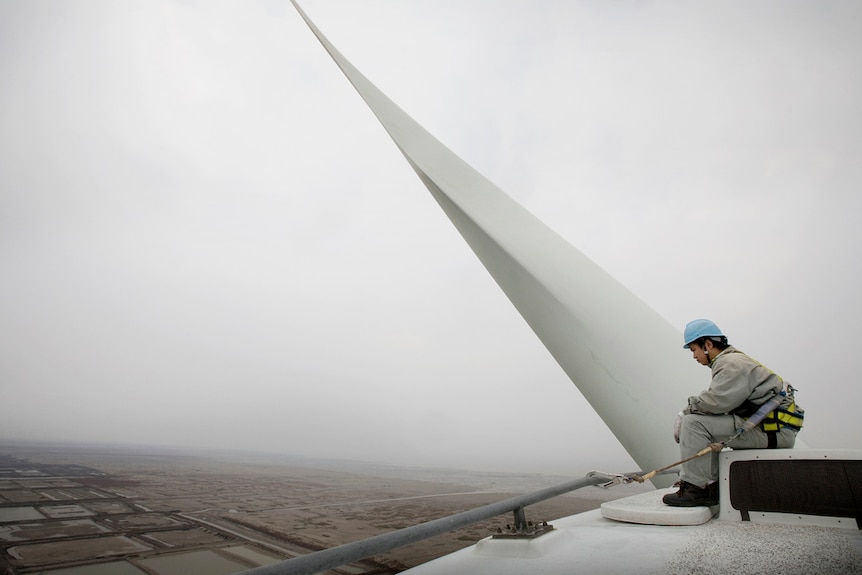 A repair man sits on top of one of the turbines at China's Xioa Yan Kou wind farm.