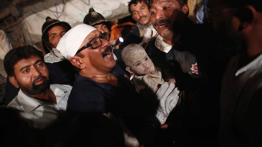 Rescue workers carry a baby who survived a building collapse