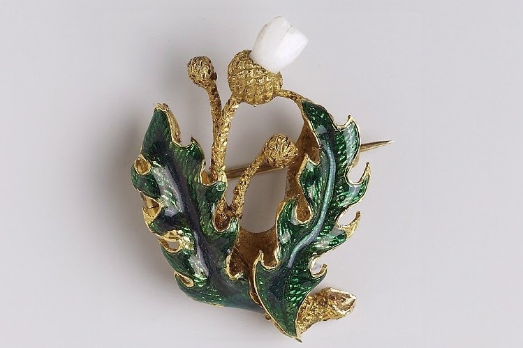 An intricate leaf brooch has a baby tooth set in its crown.