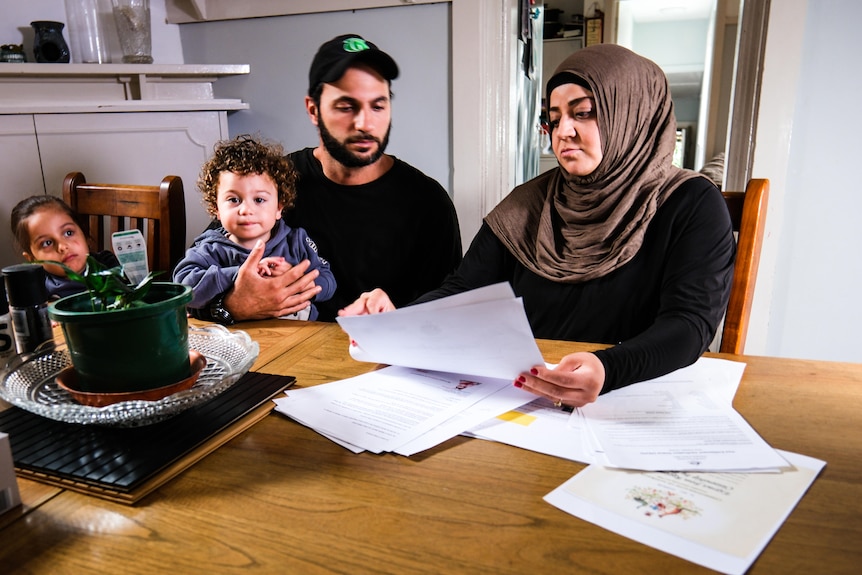 Man and woman sitting at table holding documents and children