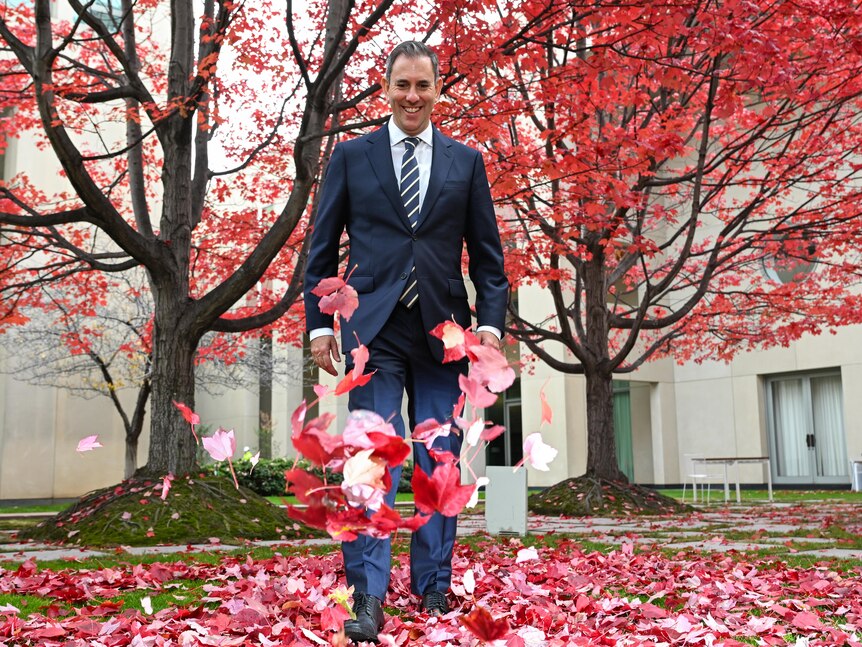 Jim Chalmers kicks red leaves in the courtyard at Parliament House.