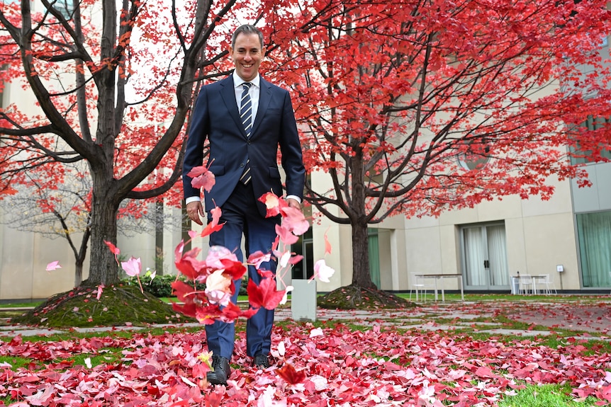 Jim Chalmers kicks red leaves in the courtyard at Parliament House.