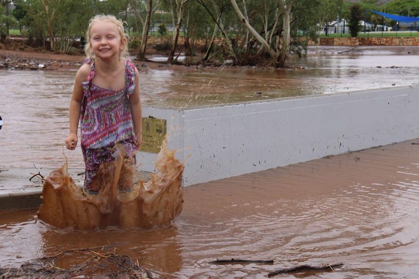 Five-year-old Taylor Galindo plays in the rain, stomping in the muddy water.