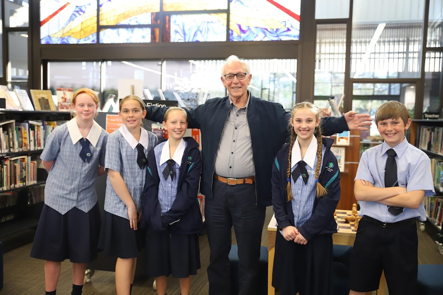 Older man standing with a group of school children looking at the camera