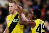 Two Richmond AFL players celebrate a goal against Essendon.