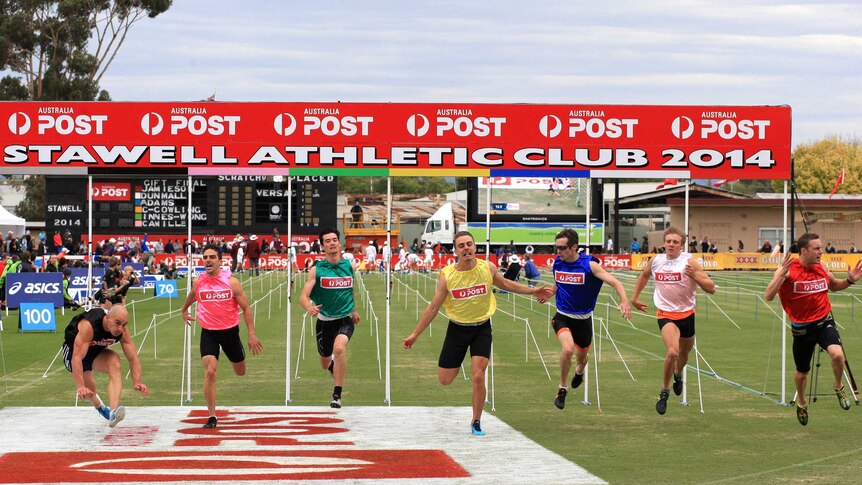 Luke Versace (left) stumbles after crossing the finish line to win the 2014 Stawell Gift.